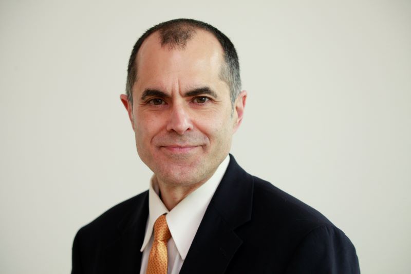 Head and shoulders image of Chris Laurent wearing a dark suit, white collared shirt and tie.