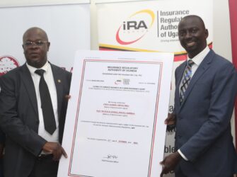 FINCA Uganda Managing Director James Onyutta and Benerd Obel, Director for Supervision, Insurance Regulatory Authority of Uganda hold poster-sized replica of FINCA Uganda's bancassurance license.